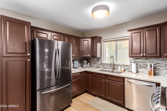 kitchen featuring backsplash, sink, light hardwood / wood-style flooring, dark brown cabinetry, and stainless steel appliances