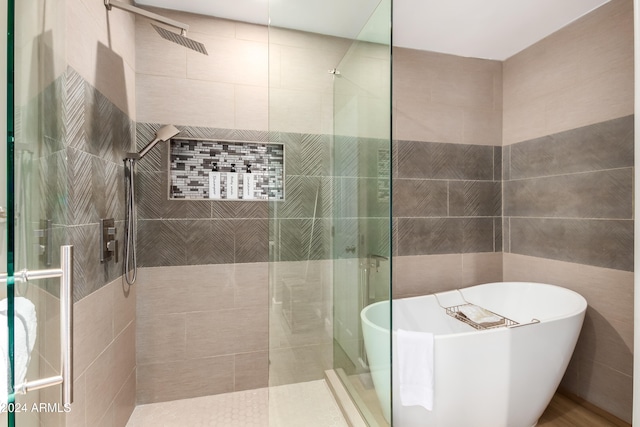 bathroom featuring separate shower and tub and tile walls