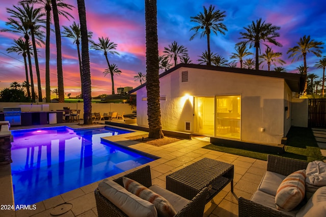 pool at dusk with outdoor lounge area, area for grilling, and a patio