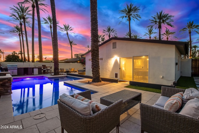 pool at dusk featuring outdoor lounge area, a grill, area for grilling, and a patio area