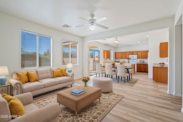 living room with ceiling fan, plenty of natural light, and light hardwood / wood-style flooring