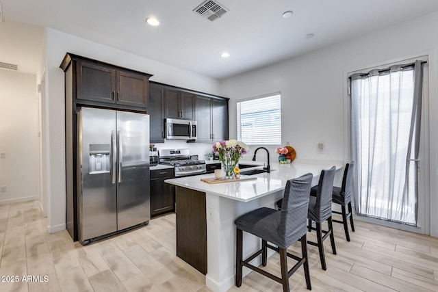 7694 W Desert Spoon Dr, Peoria, AZ 85383 - kitchen with stainless steel appliances, a breakfast bar area, dark brown cabinetry, a peninsula, and light countertops