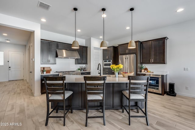 7694 W Desert Spoon Dr, Peoria, AZ 85383 - kitchen with under cabinet range hood, stainless steel appliances, a sink, light countertops, and light wood finished floors