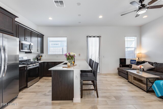 7694 W Desert Spoon Dr, Peoria, AZ 85383 - kitchen featuring stainless steel appliances, a breakfast bar area, open floor plan, recessed lighting, and light countertops