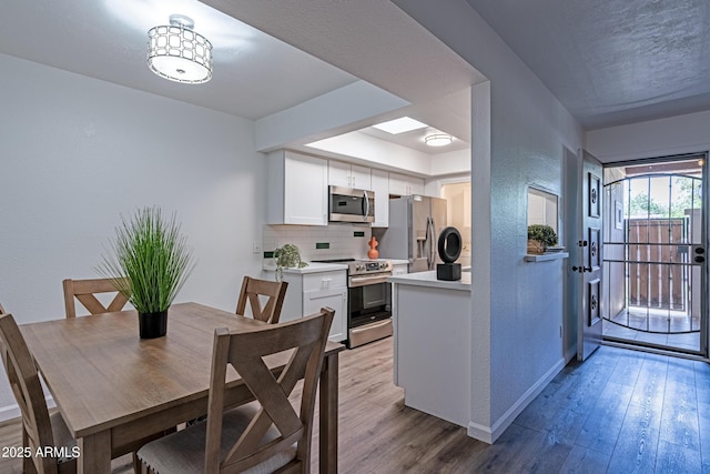 6044 W Augusta Ave, Glendale, AZ 85301 - kitchen featuring appliances with stainless steel finishes, a textured wall, baseboards, light wood-style flooring, and white cabinetry