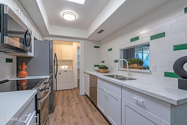 6044 W Augusta Ave, Glendale, AZ 85301 - kitchen with washer / clothes dryer, stainless steel appliances, a sink, a raised ceiling, and backsplash