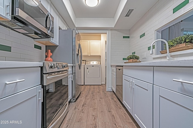 6044 W Augusta Ave, Glendale, AZ 85301 - kitchen with appliances with stainless steel finishes, independent washer and dryer, light wood-style floors, light countertops, and a tray ceiling