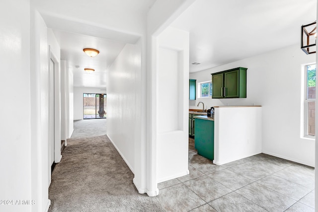 hallway with a healthy amount of sunlight, light colored carpet, and sink