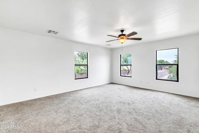 empty room featuring ceiling fan, carpet floors, and a healthy amount of sunlight