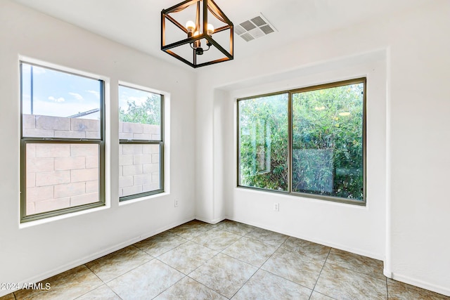 tiled empty room featuring a chandelier