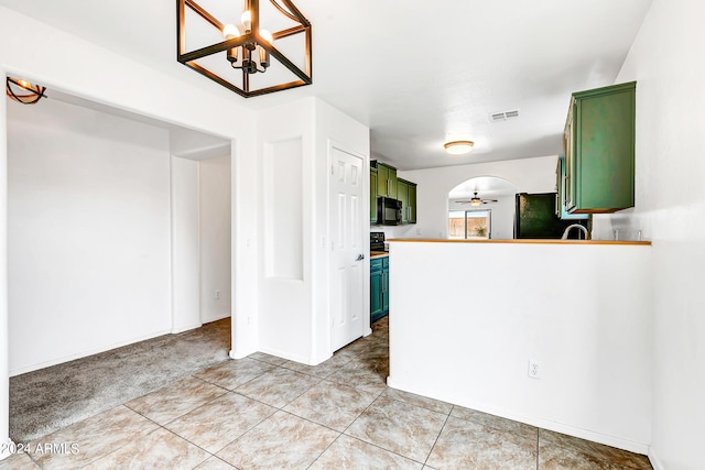 kitchen featuring ceiling fan with notable chandelier, green cabinets, refrigerator, and light tile patterned floors