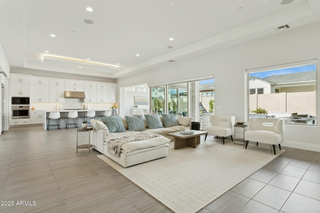 tiled living room featuring a tray ceiling