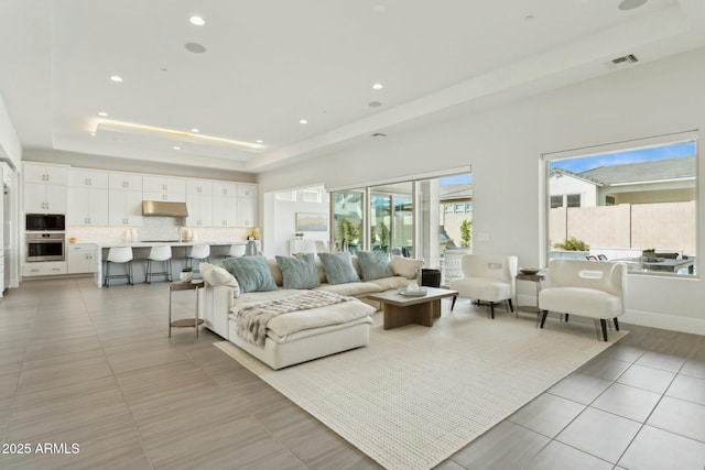 tiled living room featuring a tray ceiling