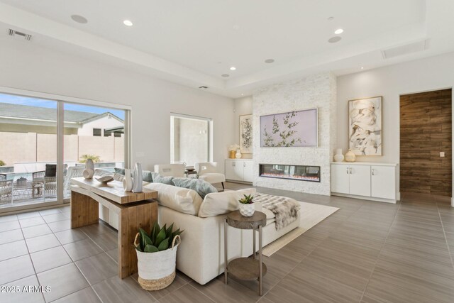 tiled living room featuring a large fireplace and a raised ceiling