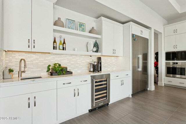 bar featuring white cabinetry, beverage cooler, built in appliances, and backsplash