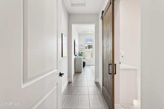 hallway with a barn door and light tile patterned floors