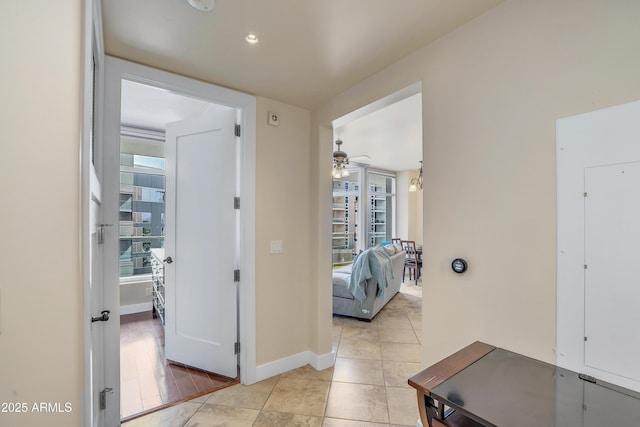 hallway featuring light tile patterned floors, baseboards, a healthy amount of sunlight, and recessed lighting