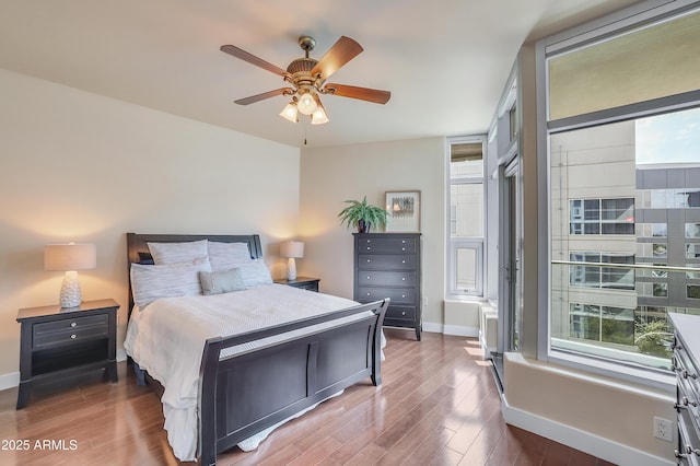bedroom with a ceiling fan, wood finished floors, and baseboards
