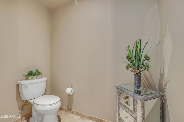 half bath featuring toilet, tile patterned flooring, and baseboards