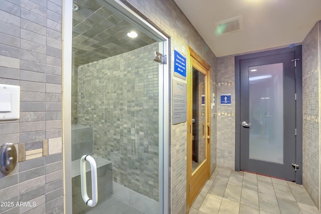 full bath featuring tile walls, tiled shower, visible vents, and tile patterned flooring