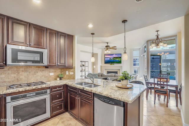 kitchen featuring light tile patterned floors, a ceiling fan, a sink, stainless steel appliances, and backsplash