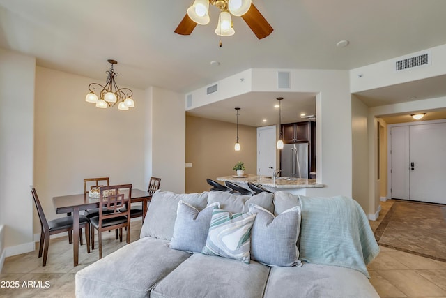living area with light tile patterned floors, visible vents, and ceiling fan with notable chandelier