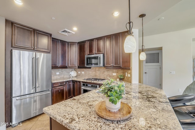 kitchen featuring light stone counters, dark brown cabinetry, a peninsula, stainless steel appliances, and tasteful backsplash