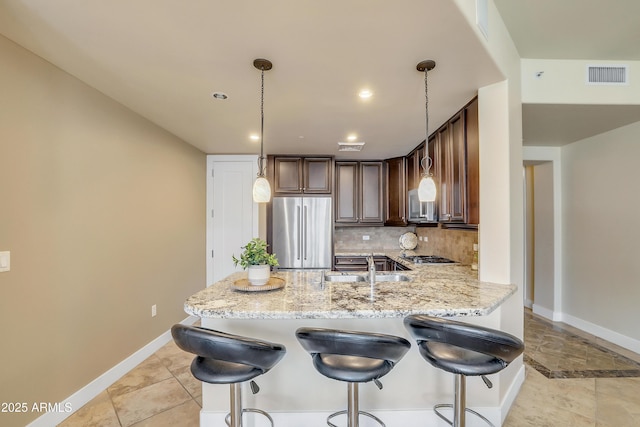 kitchen featuring decorative backsplash, stainless steel appliances, baseboards, and light stone countertops