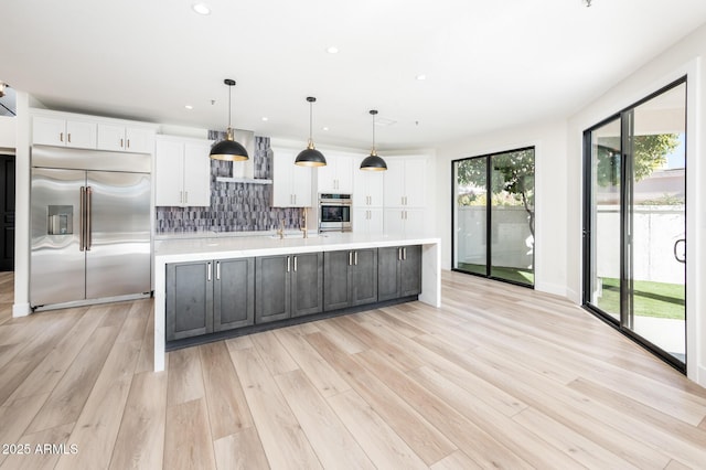 kitchen with decorative light fixtures, a spacious island, stainless steel built in fridge, and tasteful backsplash