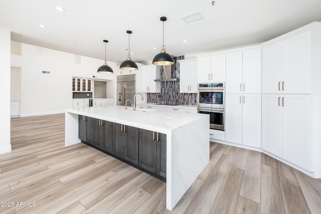 kitchen featuring appliances with stainless steel finishes, pendant lighting, white cabinets, and a spacious island