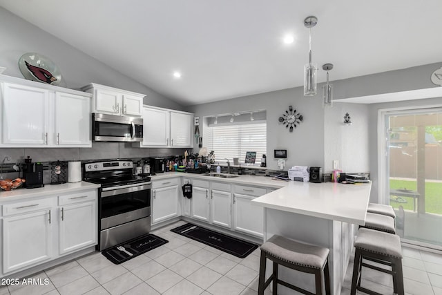 6701 W Catalina Dr, Phoenix, AZ 85033 - kitchen with white cabinets, appliances with stainless steel finishes, a breakfast bar area, a peninsula, and lofted ceiling