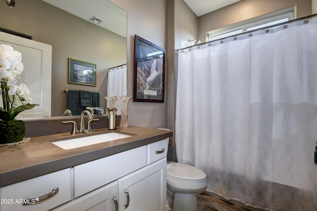 bathroom with curtained shower, toilet, and vanity