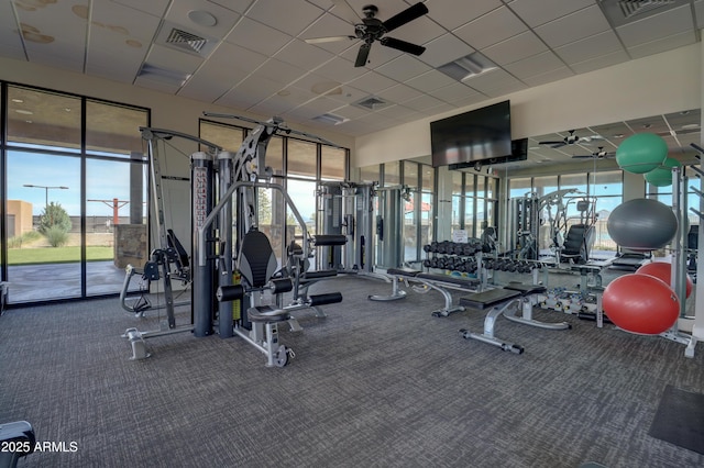 exercise room with ceiling fan and a drop ceiling