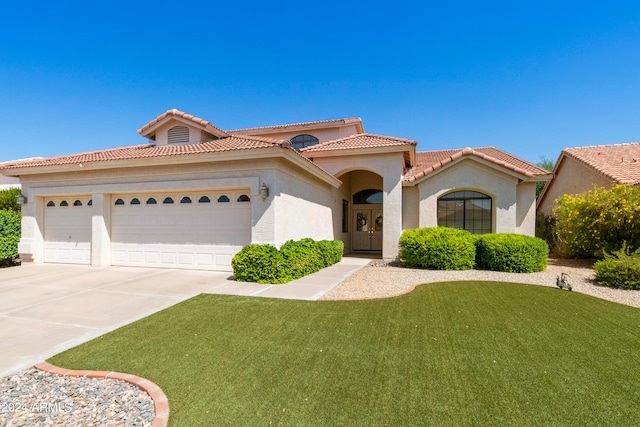 mediterranean / spanish-style house featuring a garage and a front lawn