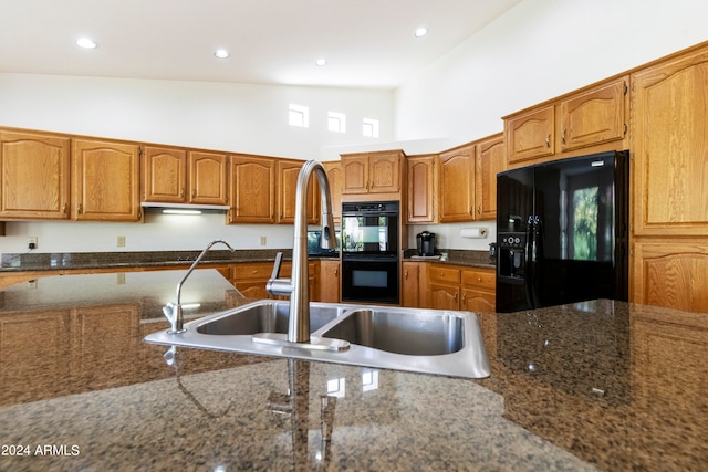 kitchen with dark stone countertops, black appliances, high vaulted ceiling, and sink