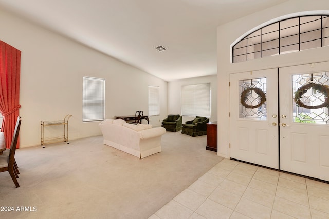 foyer entrance featuring lofted ceiling, light carpet, and french doors