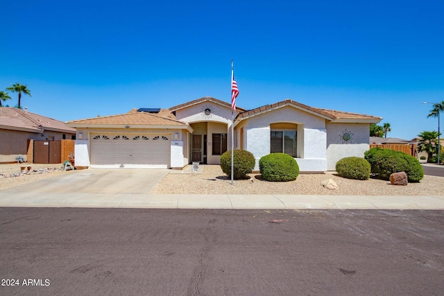 view of front facade with a garage, driveway, fence, and stucco siding