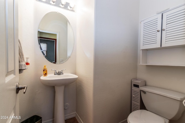 half bath featuring toilet, baseboards, and a sink