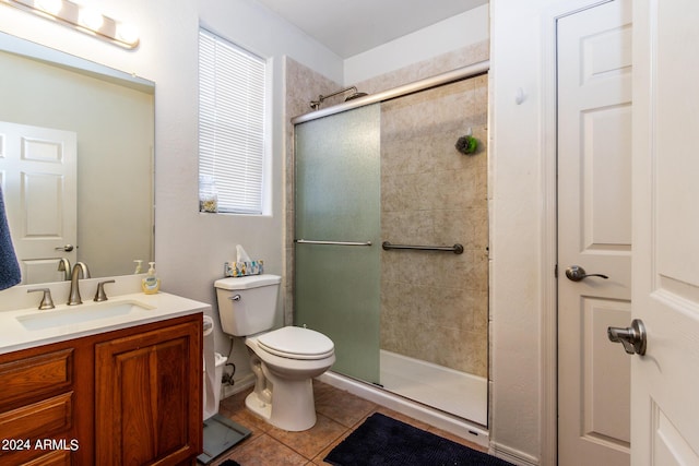 bathroom with a tile shower, vanity, toilet, and tile patterned floors