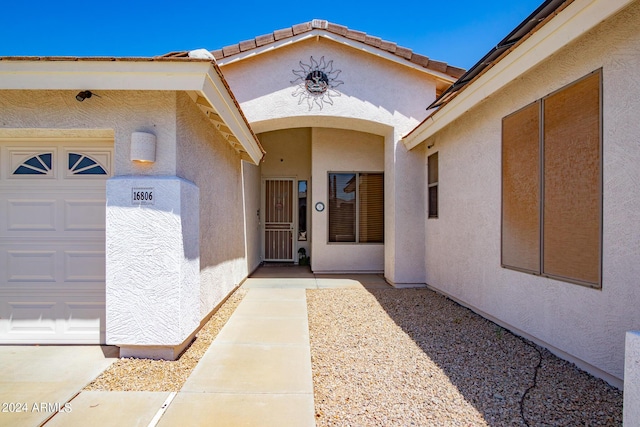 doorway to property with an attached garage and stucco siding