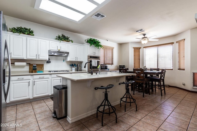 kitchen featuring light tile patterned floors, under cabinet range hood, visible vents, light countertops, and appliances with stainless steel finishes