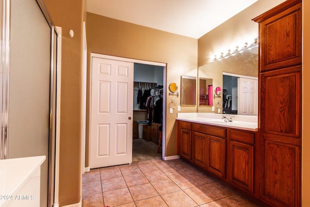 bathroom with tile patterned flooring, a spacious closet, and vanity