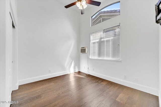 unfurnished room featuring ceiling fan, hardwood / wood-style flooring, and a wall mounted air conditioner