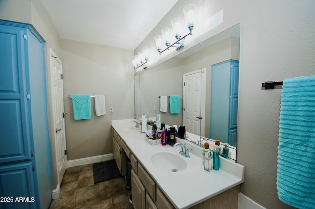 full bathroom featuring double vanity, baseboards, and a sink