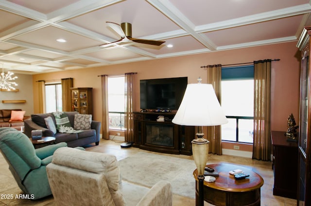 living room featuring plenty of natural light, ceiling fan with notable chandelier, coffered ceiling, and a glass covered fireplace