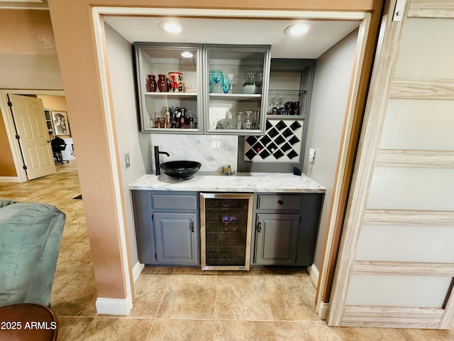 bar with a bar, beverage cooler, baseboards, and tasteful backsplash