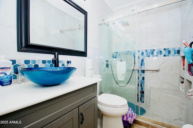 full bath with a stall shower, toilet, backsplash, vanity, and tile walls