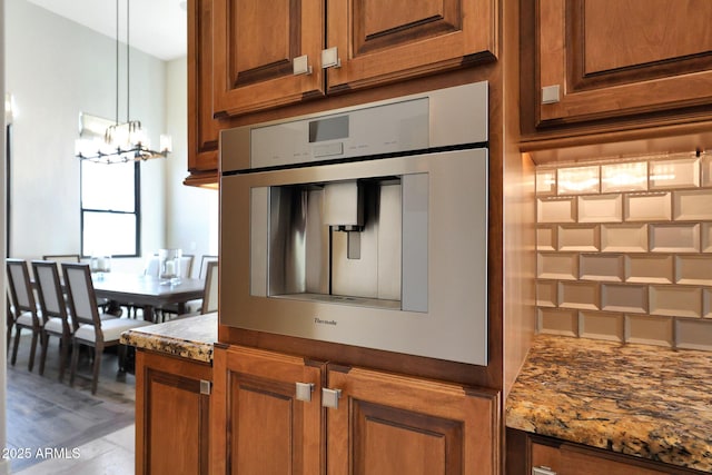 kitchen featuring dark stone counters, oven, a notable chandelier, and hanging light fixtures