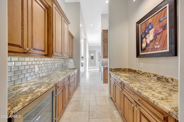 kitchen featuring light stone countertops, wine cooler, decorative backsplash, and sink