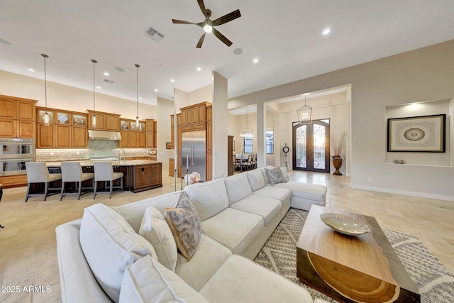 living room featuring french doors and ceiling fan with notable chandelier